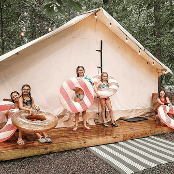 alpha wall tent set up on a platform with kids thoroughly enjoying